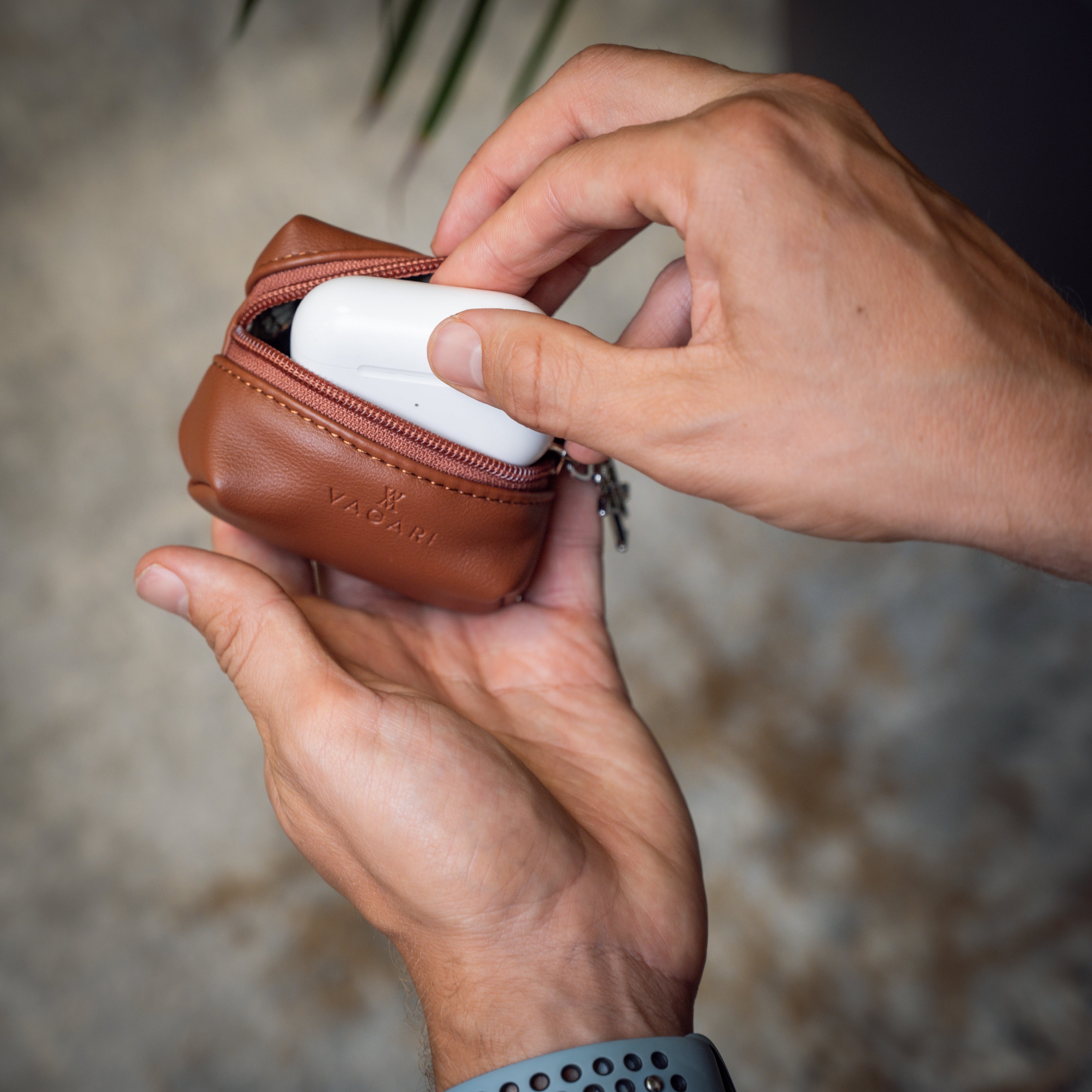 Lifestyle POV of the Memphis Earbud Case in Tan opened to reveal earbuds in charging case