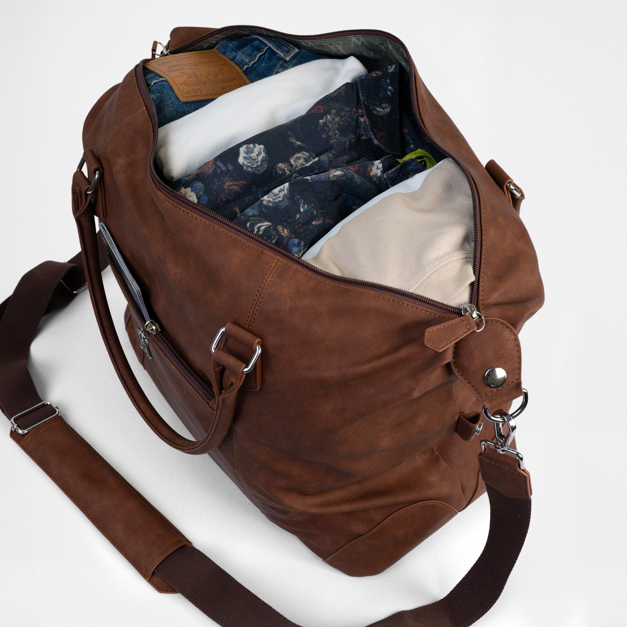 Open top view of the Lisbon Weekender in Cognac, showing spacious interior neatly filled with clothing and detachable shoulder strap.