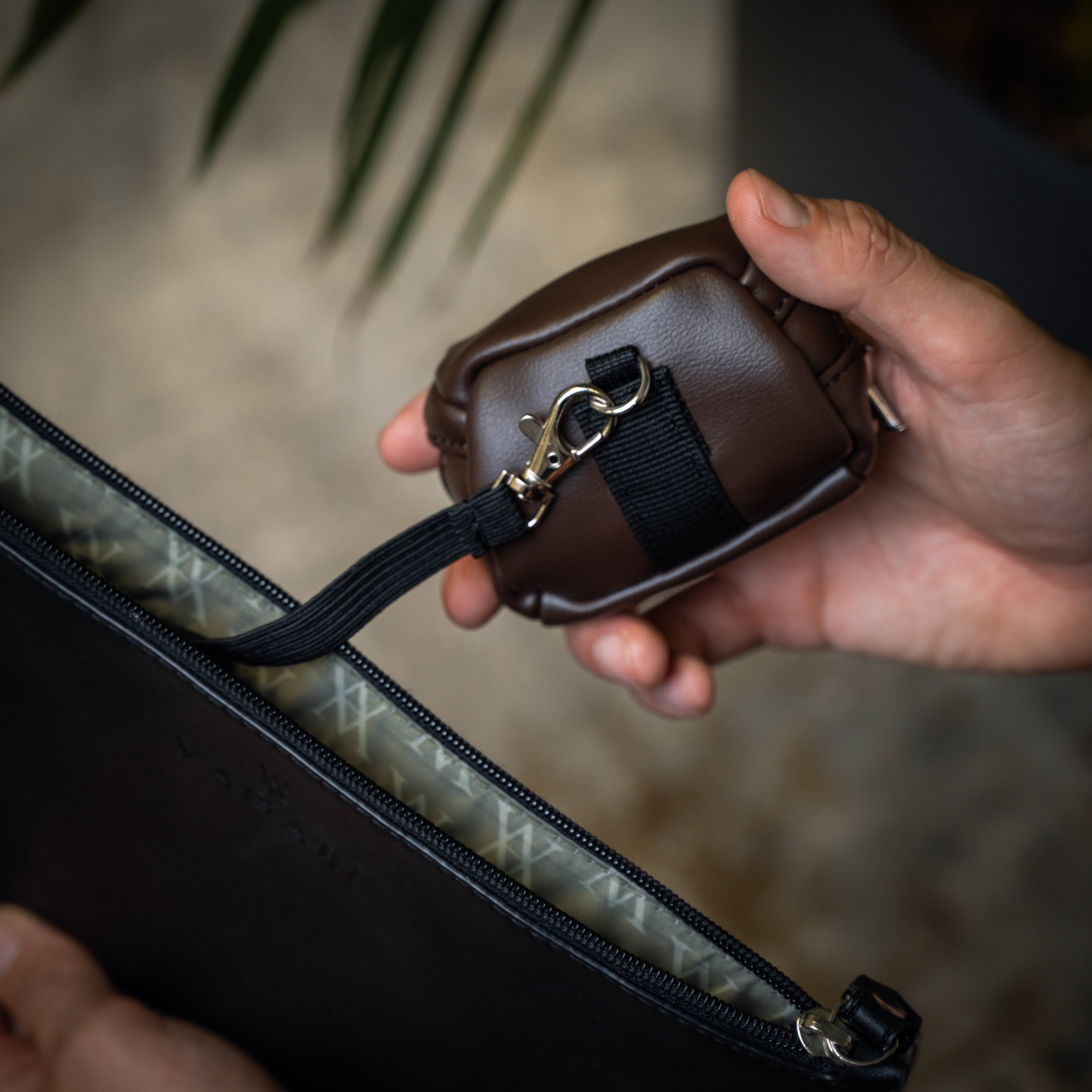 Lifestyle POV of the Memphis Earbud Case in Chocolate with clip attached to pouch