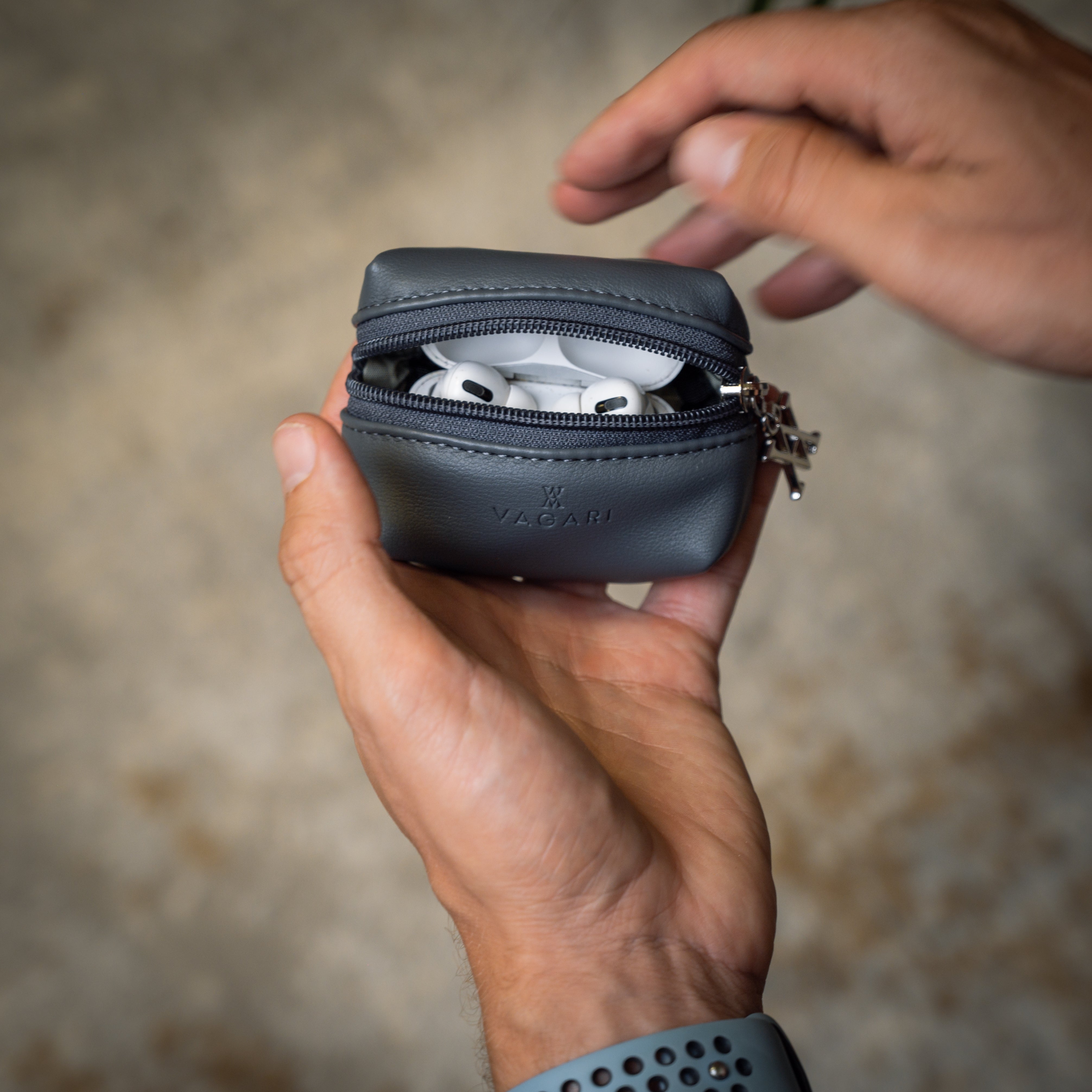 Lifestyle POV of the Memphis Earbud Case in Graphite being opened to reveal earbuds