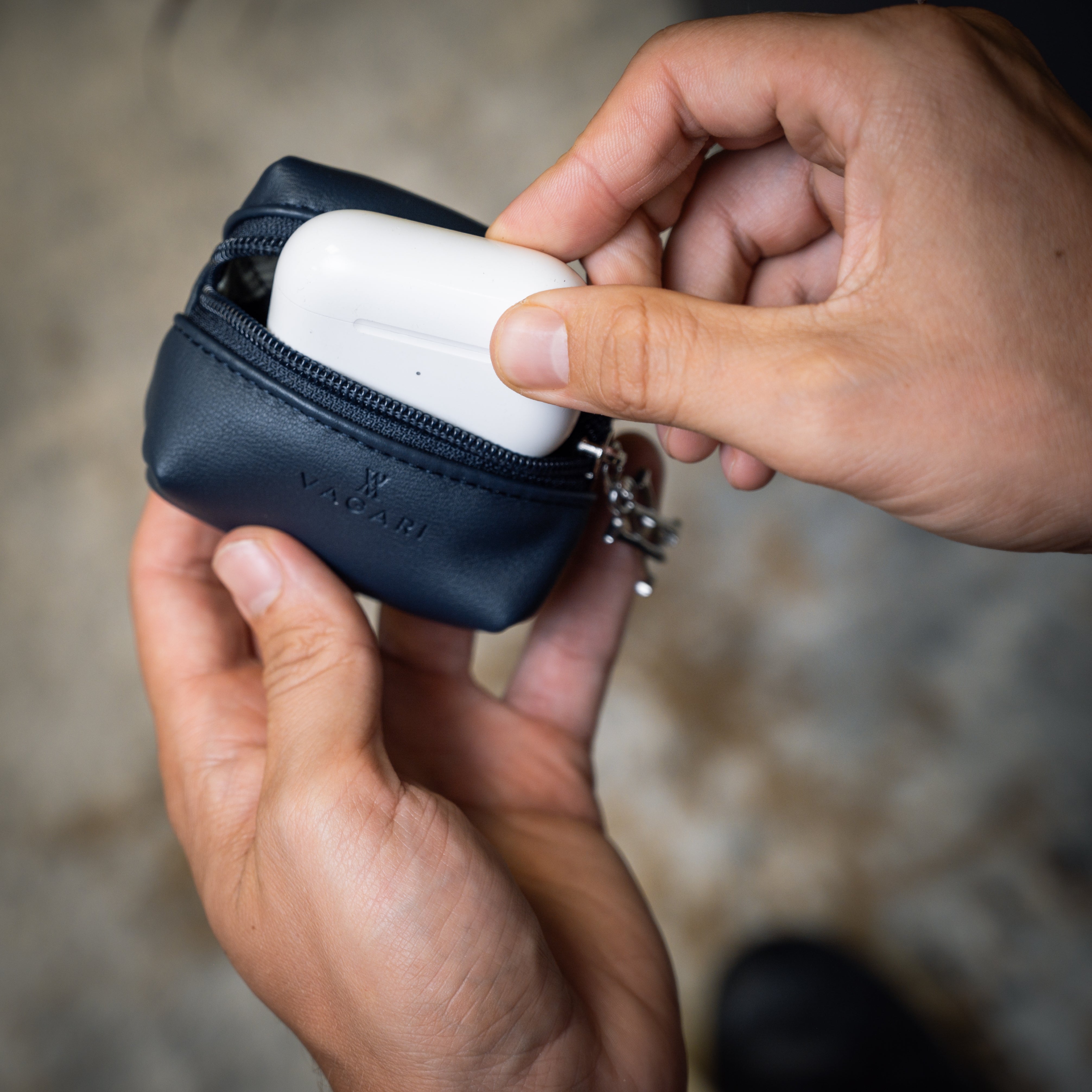 Lifestyle POV of the Memphis Earbud Case in Navy opened to reveal earbuds in charger