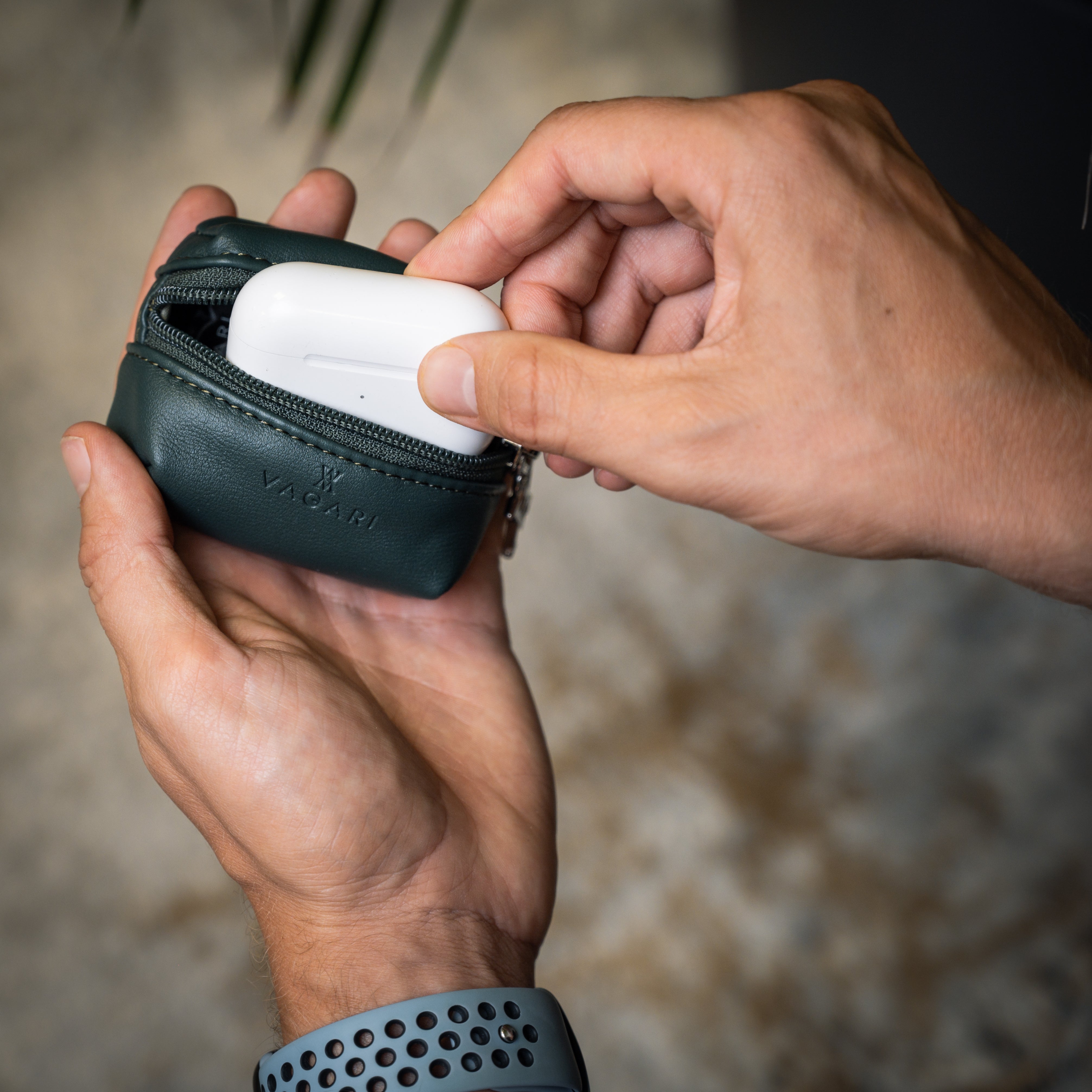 Lifestyle POV of the Memphis Earbud Case in Racing Green being opened to access earbuds in charging case