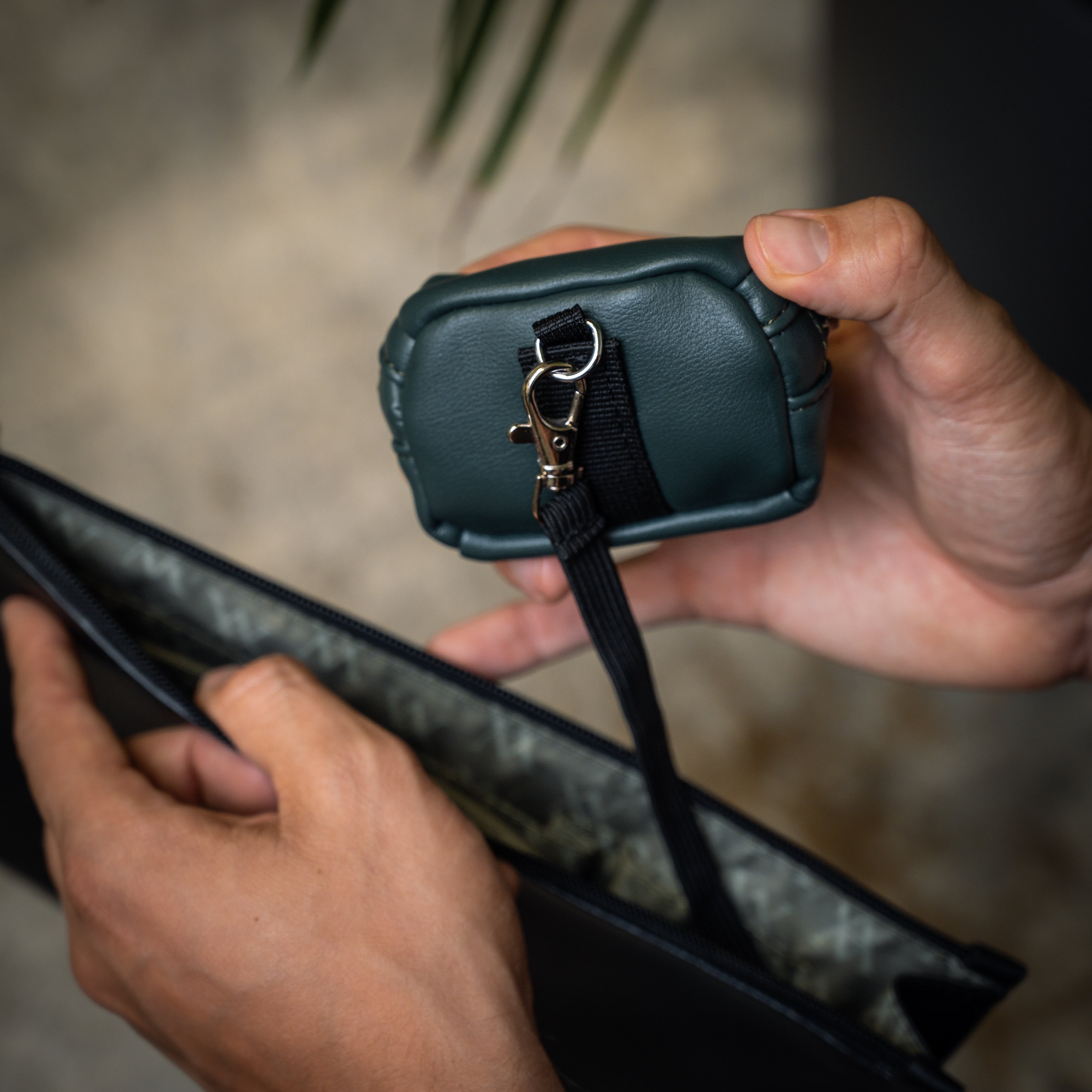 Lifestyle POV of the Memphis Earbud Case in Racing Green with clip attached to pouch
