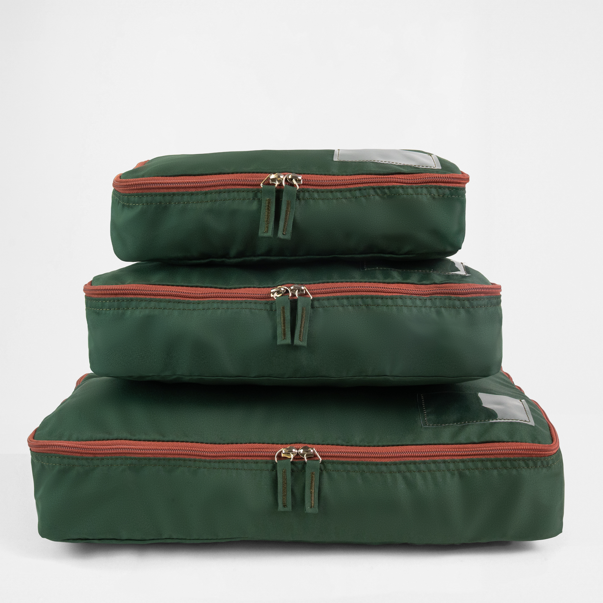 A set of three racing green packing cubes of different sizes stacked.